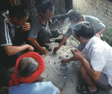 陰雨天,三五瑤民聚在一起玩瑤族傳統(tǒng)“趕豬棋”。